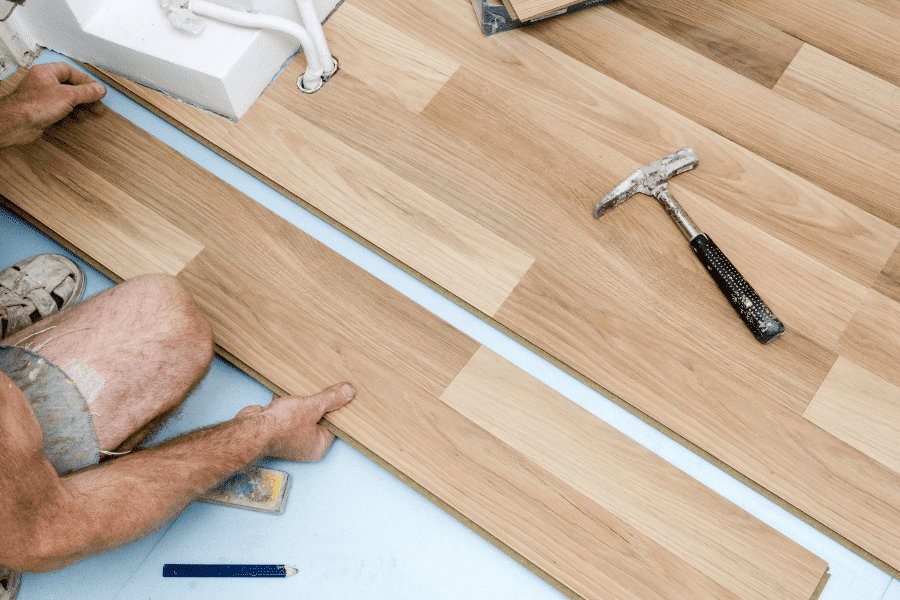 floor installers putting down a hardwood plank on the floor